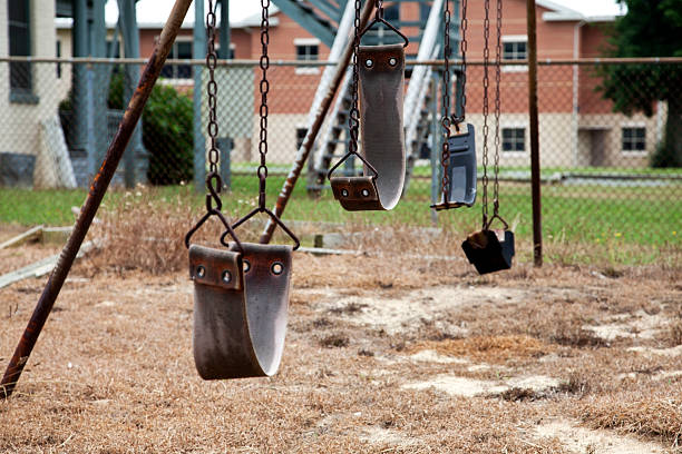 Aging Swings Schoolyard swings. Rusting chains, Disuse. Horizontal. run down stock pictures, royalty-free photos & images