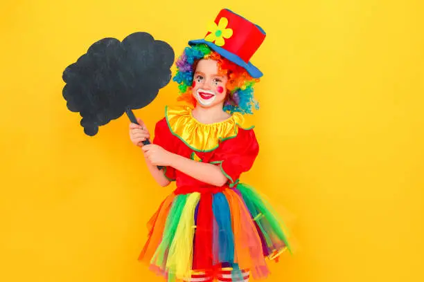 Photo of Little girl in clown costume and hat holding black table