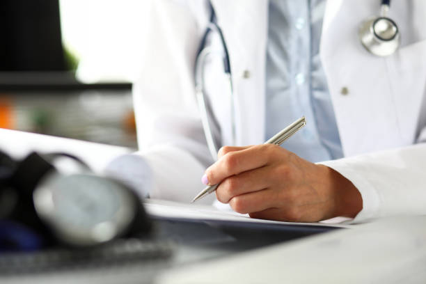 istock Hands of female GP making notes with silver pen 1182762492