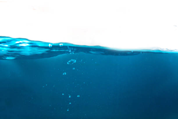 close-up shot of blue water surface and shining blue bubbles underwater with white background