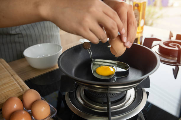 istock Hands breaking an egg into heart block in a pan 1182771195