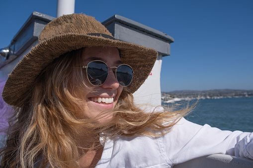 A beautiful young woman on a ferry boat smiles and looks to the left.