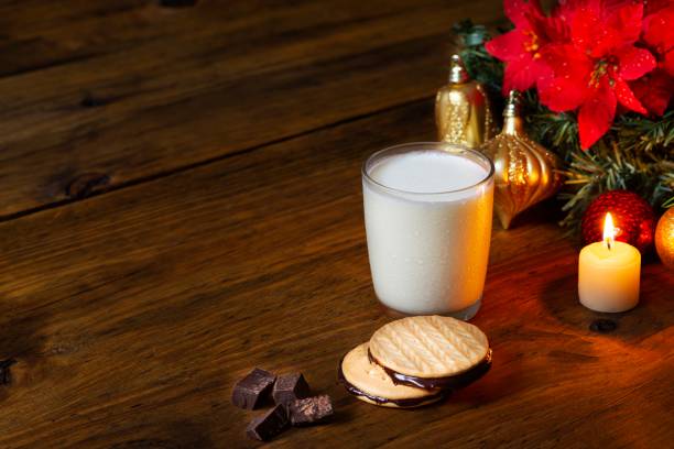 chocolate cookies and milk in christmas season - poinsettia christmas candle table imagens e fotografias de stock