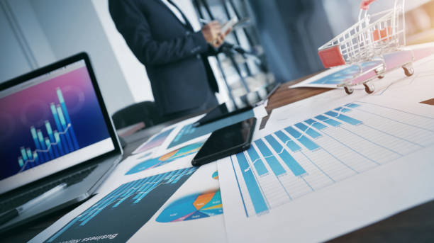 istock Businessman writing information on notepad and analyzing sales data with financial business growth graph on laptop and paperwork, Business planning and strategy 1182777180