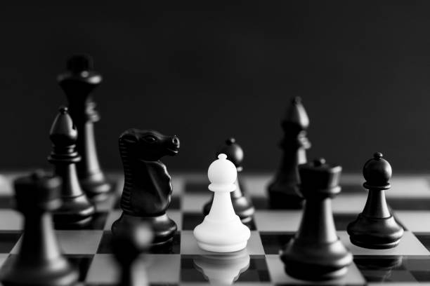 White pawn and black chess pieces on chessboard White pawn and black chess pieces on chessboard. black knight stock pictures, royalty-free photos & images