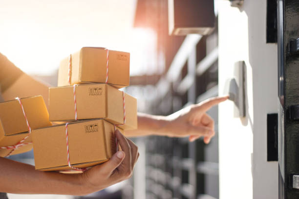 Delivery man holding parcel boxes and ring the doorbell on the client's door in the morning background. Delivery man holding parcel boxes and ring the doorbell on the client's door in the morning background. receiving box stock pictures, royalty-free photos & images