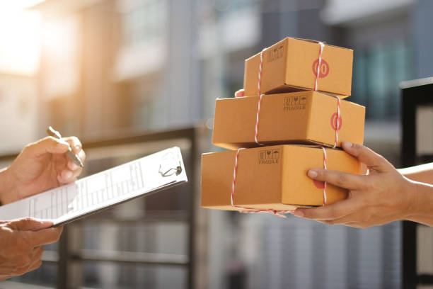 istock Delivery man holding parcel boxes while a man is signing documents in morning background 1182778656