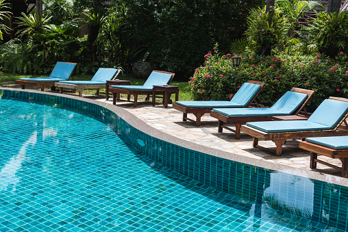 Nobody lounge chairs near swimming pool in hotel resort