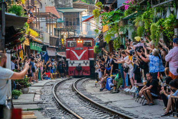 View of train passing through a narrow street of the Hanoi Old Quarter. HANOI, VIETNAM - OCT 6, 2019 : View of train passing through a narrow street of the Hanoi Old Quarter. Tourists taking pictures of hurtling train. The Hanoi Train Street is a popular attraction. hanoi stock pictures, royalty-free photos & images