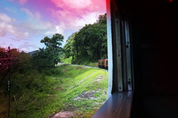 istock View from train railway makes a curve bend through beautiful natural green grasslands and mountains . Travel in Thailand , Effect saturation 1182788922
