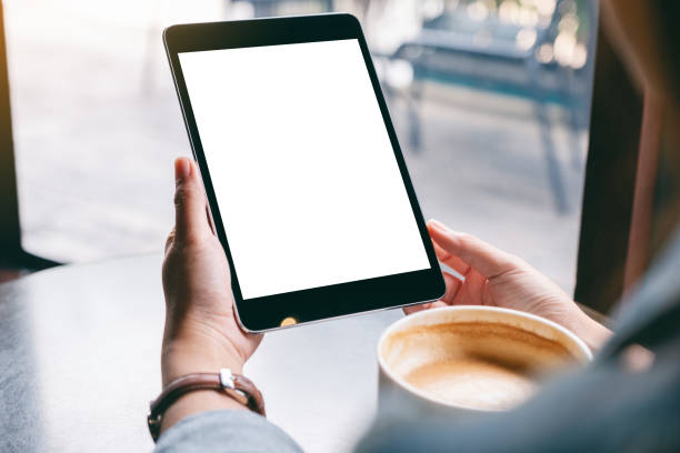 istock a woman holding black tablet with white blank screen and coffee cup on the table 1182792285