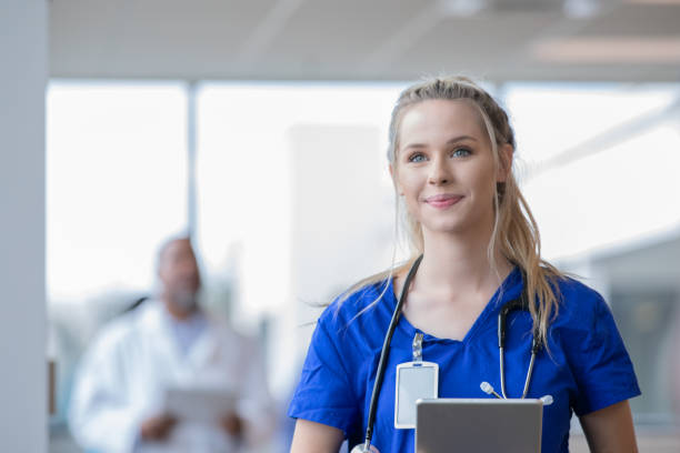 studente infermieristico o stagista medico sorride mentre cammina in ospedale - lab coat nurse doctor female doctor foto e immagini stock