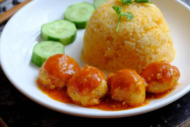 Close up Vietnamese vegan rice dish with meatballs from tofu ball with tomato sauce, cucumber for vegetarian lunch meal, homemade delicious and safe, healthy food from Vegetal diet