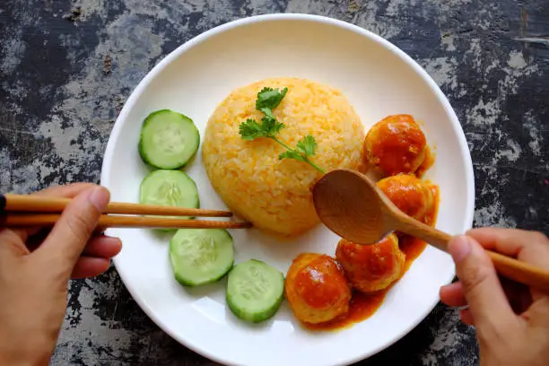 Top view people eating Vietnamese vegan rice dish with meatballs from tofu ball with tomato sauce, cucumber for vegetarian lunch meal, homemade delicious and safe, healthy food from Vegetal diet