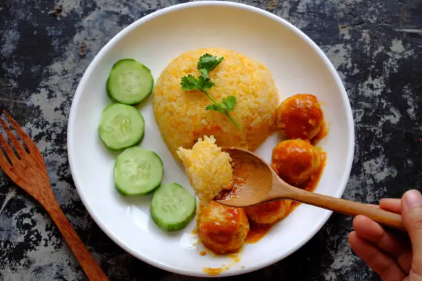 Top view people eating Vietnamese vegan rice dish with meatballs from tofu ball with tomato sauce, cucumber for vegetarian lunch meal, homemade delicious and safe, healthy food from Vegetal diet