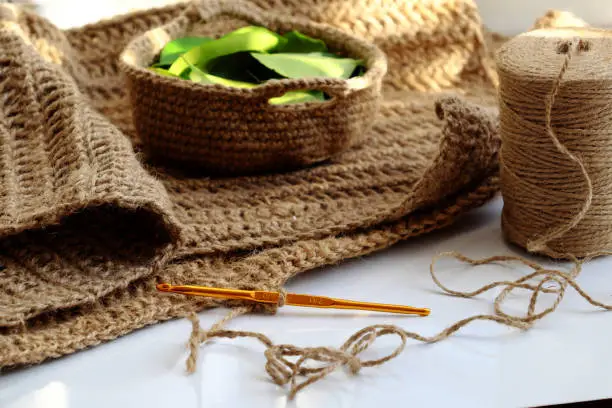 Close up crochet hook with ball of jute rope to make decor handmade product, table dishcloth or mat on white background