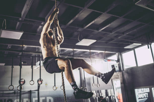 istock Young athletic man exercising strength on a rope in a gym. 1182798937