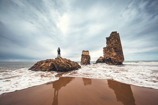 Man standing on the ruins of Torre del Rio de Oro on the beach in Mazagon, the province of Huelva, Andalusia, Spain.