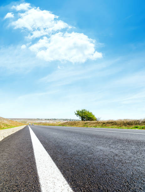 istock asphalt road with white line closeup and blue sky with white clouds 1182801454