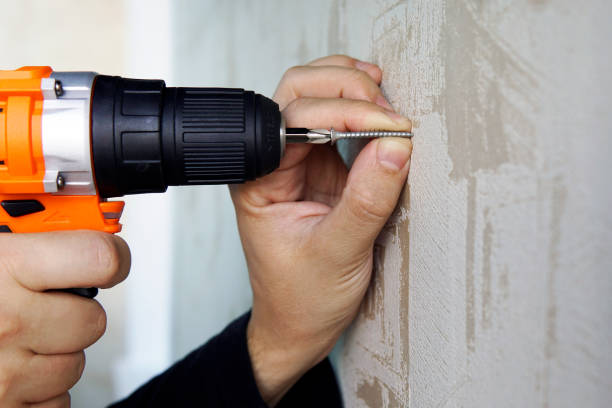 atornillar un tornillo en la pared con un destornillador eléctrico de cerca. reparación en el apartamento o casa. - drill equipment dirty work tool fotografías e imágenes de stock