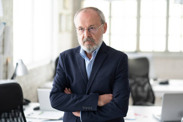 istock Senior businessman standing in modern workplace 1182802949