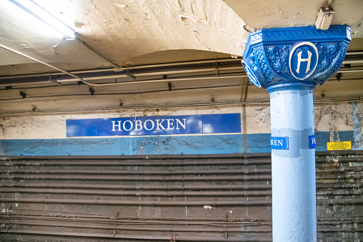 A metro sign for the Paris underground, with a light bulb on the top. Dusk. Blue sky in the background.