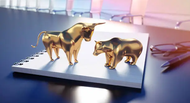 Golden Bull and Bear standing on a Notebook in an Office Room