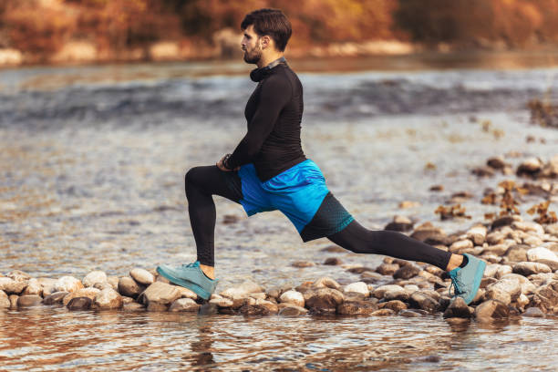 istock Handsome young man stretching on river bank. 1182812511