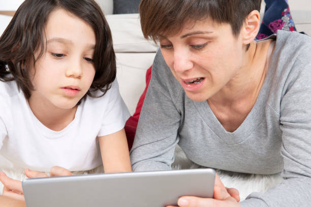 istock Mother and son laying on carpet using digital tablet 1182812828