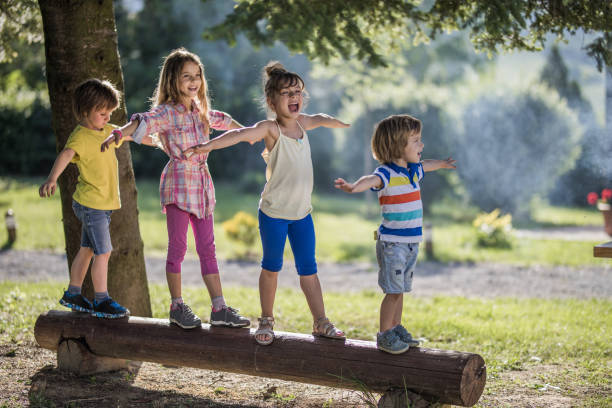 istock Group of small kids walking on a tree trunk in nature. 1182812901