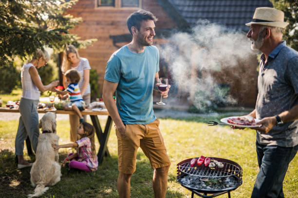 istock Happy men talking while preparing barbecue for his family in the backyard. 1182813548