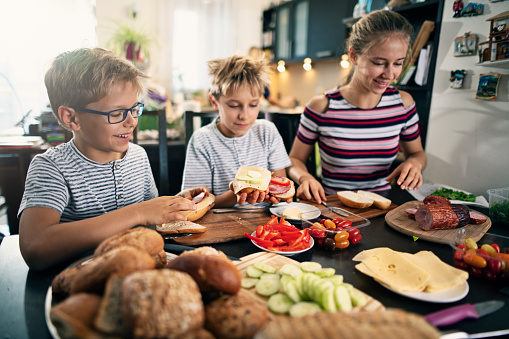 Kids making sandwiches for school.
There is some ham, bread, tomato, cheese, pepper and cucumber on the table.
Nikon D850