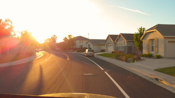 レンズフレア:日没時に豊かな地域の風光明媚な通りを運転。 - house residential district residential structure car ストックフォトと画像