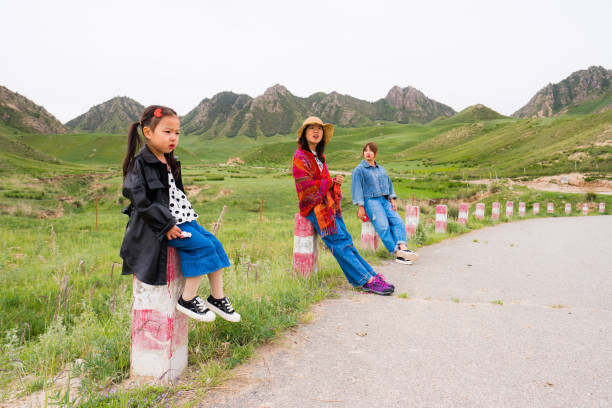 mother and two daughters sitting by the road