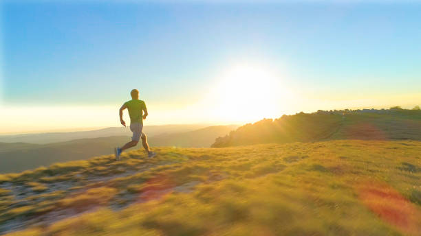 istock LENS FLARE: Athletic young man sprints down a grassy hill on a sunny morning 1182820125