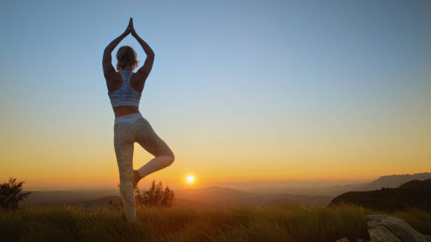 istock LOW ANGLE: Young woman standing on one leg while doing yoga at beautiful sunset. 1182820636