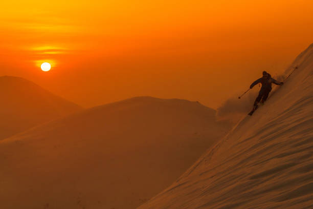 silhouette: spektakuläre aufnahme von profi-skifahrern, die an einem sonnigen abend abseits der loipe fahren. - carving skiing stock-fotos und bilder