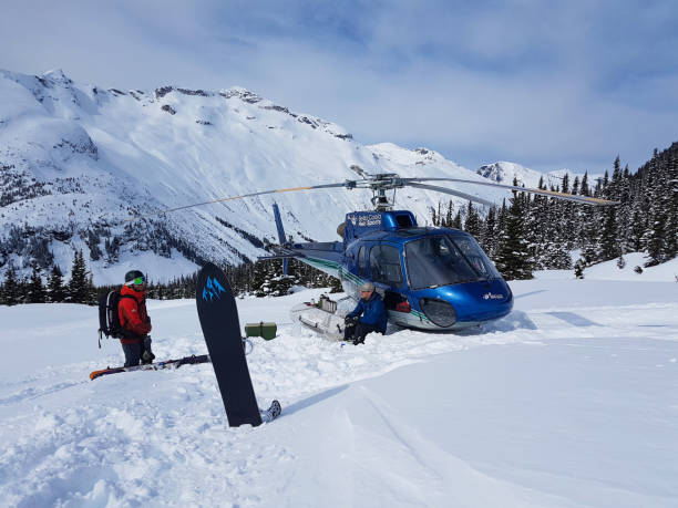 extreme snowboardåkare och pilot talk av den blå helikoptern parkerad i bergen. - heliskiing bildbanksfoton och bilder