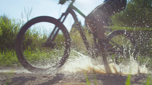 istock LOW ANGLE: Unrecognizable active person rides their bike into a muddy puddle. 1182820919