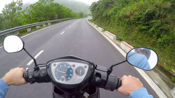istock POV: Riding a motorcycle along empty road leading through the tropical forest. 1182821658