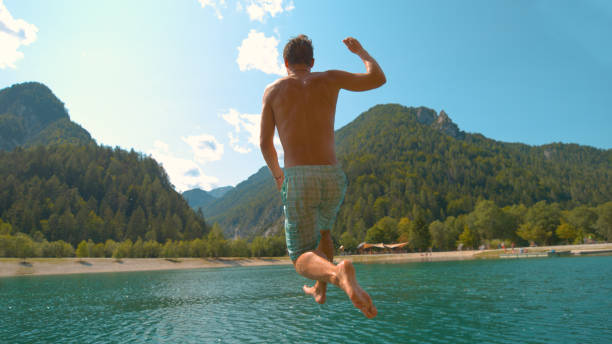 istock CLOSE UP: Unrecognizable man runs off the pier and jumps into refreshing lake 1182822132