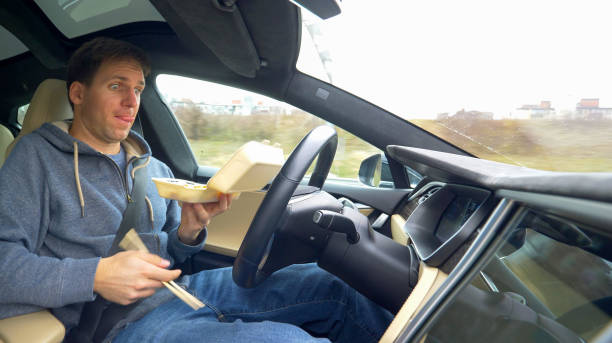 istock CLOSE UP: Male driver eating while driving home in a self steering vehicle. 1182822406