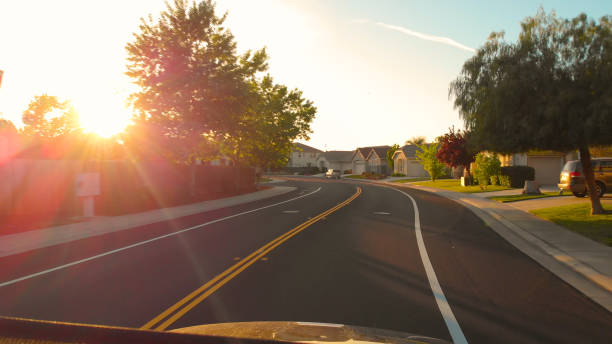 POV: Driving through the tranquil suburban neighborhood in California at sunset. POV LENS FLARE: Driving through the tranquil modern suburban neighborhood in California at picturesque autumn sunset. Scenic cruise past stunning luxury properties on the outskirts of San Francisco. car point of view stock pictures, royalty-free photos & images