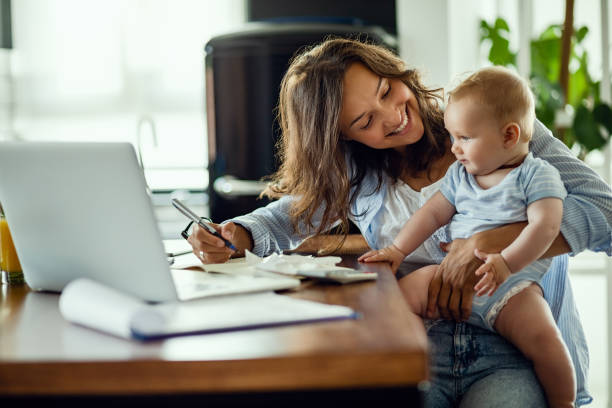 madre felice che parla con il suo bambino mentre lavora a casa. - business relations foto e immagini stock