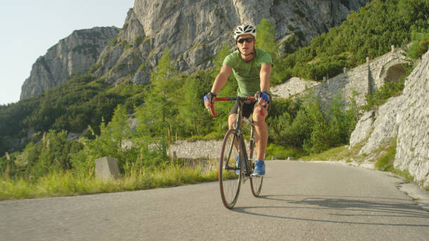 istock LOW ANGLE: Athletic man riding his road bicycle down the empty asphalt road. 1182824420