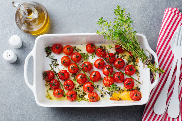 istock Roasted cherry tomatoes with herbs in baking dish. Grey background. Top view. 1182824675