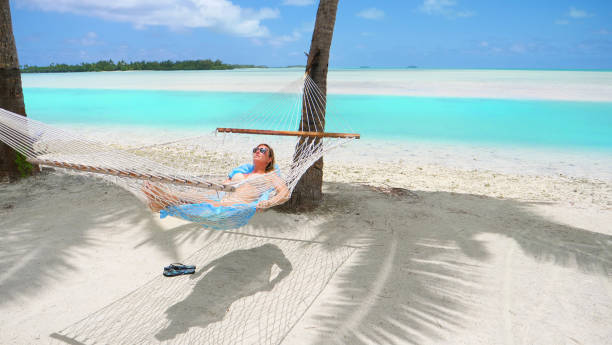 istock CLOSE UP: Cheerful young woman relaxing under the palms in a comfortable hammock 1182825611