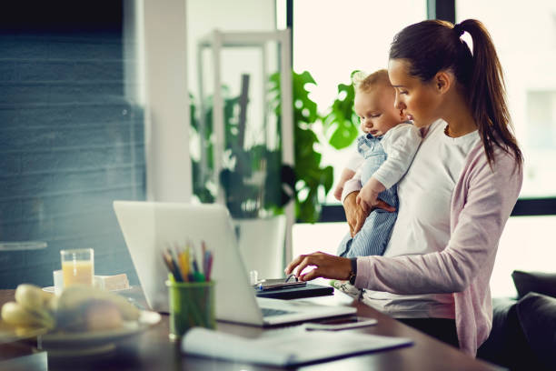 istock Young mother with baby son using computer at home. 1182828032