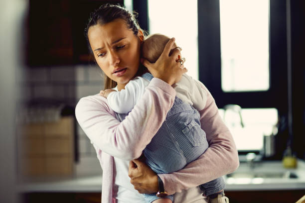 It's all right dear, mom is here! Young mother holding her baby son and consoling him at home. postpartum depression stock pictures, royalty-free photos & images