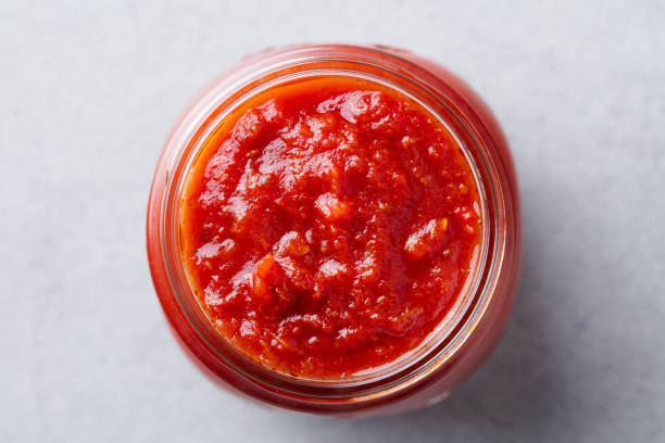 томатный соус в стеклянной банке. серый фон. заживать. вид сверху. - tomato sauce jar стоковые фото и изображения